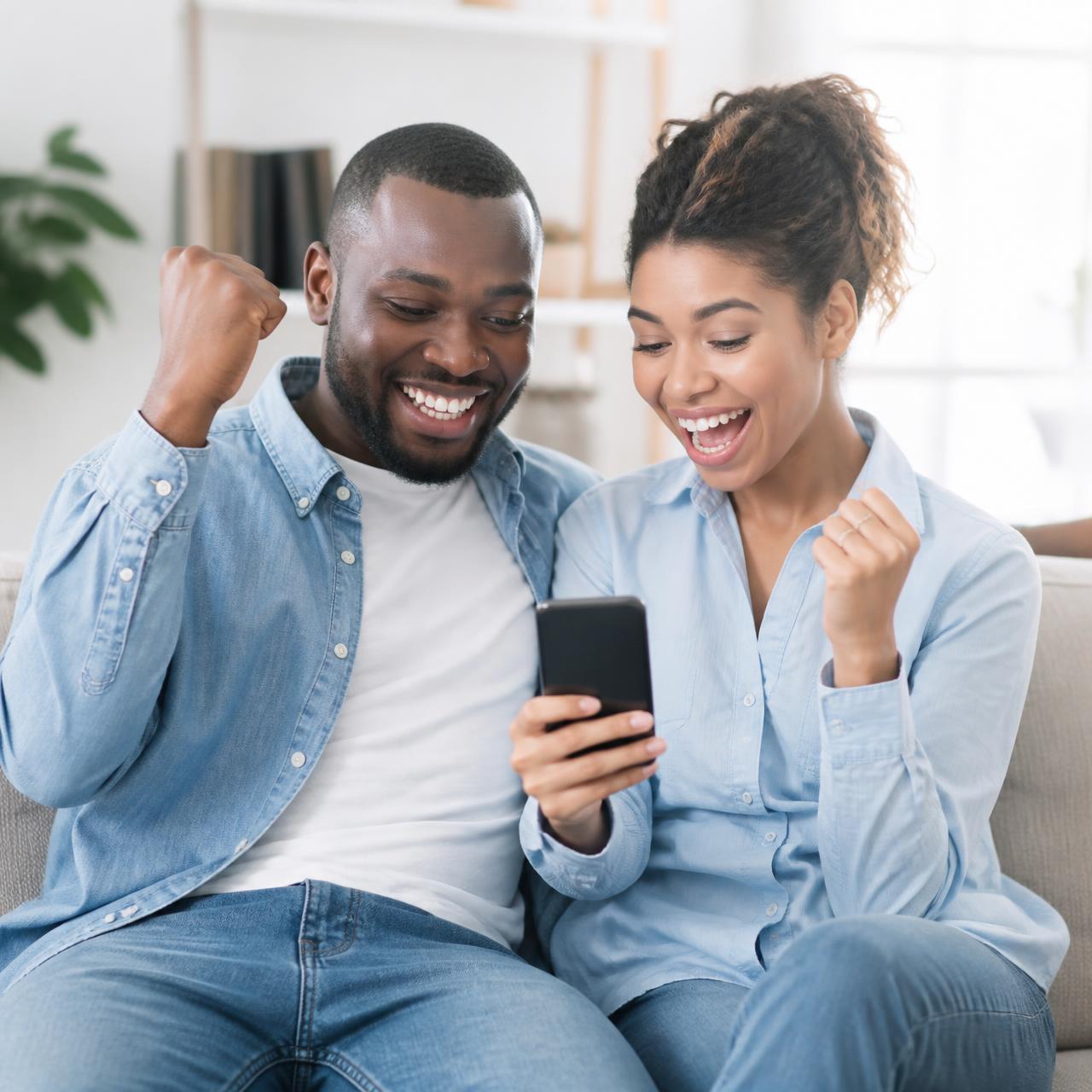 A smiling couple celebrating together while checking their credit score on a phone.